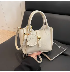 Detail of cream lychee texture leather bucket bag with gold clasp and dog charm