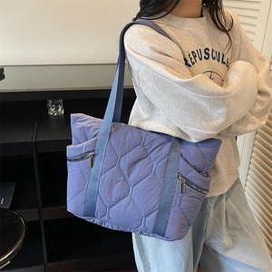 Blue quilted nylon tote bag with rhombus stitching and silver side zippers for commuting