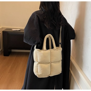 Close-up of beige quilted tote bag with large square padding and shoulder strap detail