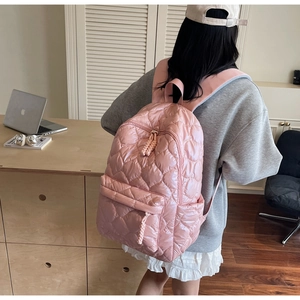 Detail of pink quilted puffer backpack with zip pockets worn by a model in a cozy setting