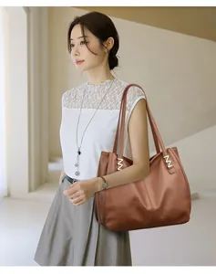 Detail of caramel pebbled leather tote with golden M-shaped metal hardware and large capacity