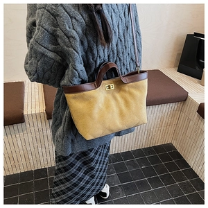 Détail du sac fourre-tout matelassé jaune avec finitions en cuir brun et fermoir doré