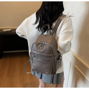 Close-up of a taupe lychee leather backpack showing detailed texture and silver zippers