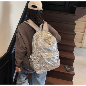 Detail of silver metallic puffer backpack featuring quilted bear patterns and rope puller