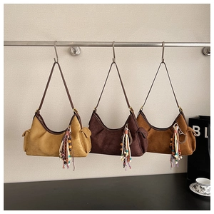 Trois sacs à bandoulière demi-lune en daim marron avec des pendentifs à pompons colorés