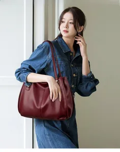 Detail of burgundy lychee grain leather tote bag with long shoulder strap in a minimalist style