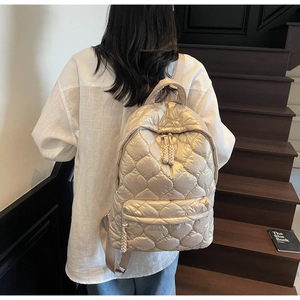 Detail of champagne gold quilted backpack featuring elegant heart-shaped padded stitching