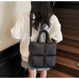 Quilted puffer tote bag in black featuring adjustable shoulder strap and soft texture