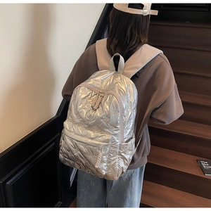 Detailed view of silver quilted backpack with metallic finish and bow texture