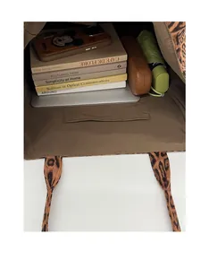 Detail shot showing the large capacity interior of a leopard print tote bag with books