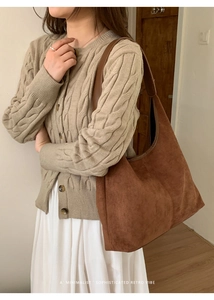 Detail of a large brown suede tote bag worn with a knit cardigan in a retro aesthetic