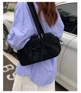 Détail du sac bandoulière en velours côtelé noir avec nœuds latéraux et boucles en métal