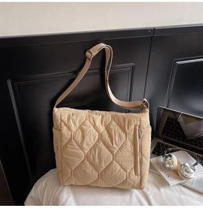 Close-up of beige quilted tote bag with front zipper and adjustable strap in lifestyle setting