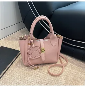 Detail of pink lychee textured leather tote with gold hardware and cute dog charm