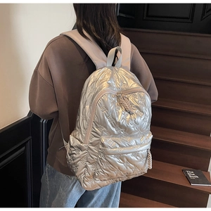 Close-up of metallic silver quilted backpack with bow texture and zipper cord detail