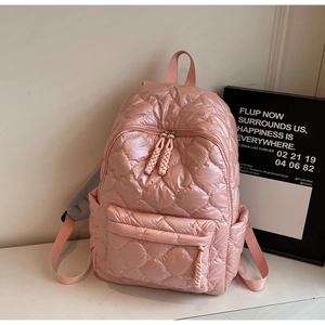 Detail of pink quilted cotton backpack with glossy rhombic texture and woven cord pullers
