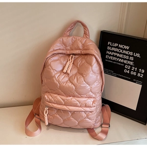 Detail of pink quilted nylon backpack with padded texture and braided zipper pullers