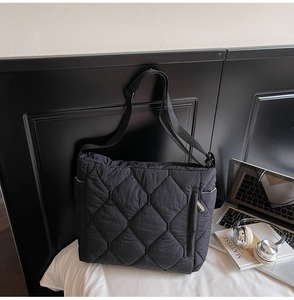 Detailed macro view of black quilted puffer bag with diamond stitching and adjustable strap