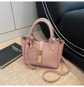 Detail of pink lychee grain leather bucket bag with cute dog charm and gold hardware