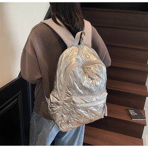 Close-up detail of silver metallic quilted backpack with butterfly patterns and woven pullers