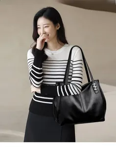 Close-up of black textured leather tote bag showing large capacity and silver buckle detail
