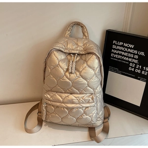 Detailed shot of champagne gold quilted backpack with metallic finish and woven zip pulls