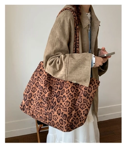 Detail of leopard print tote bag with wide shoulder strap worn with an elegant coat