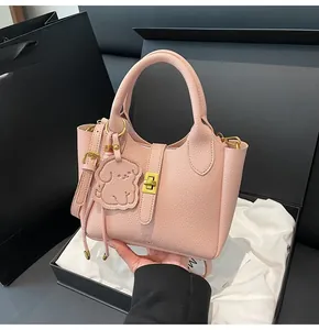 Detailed view of pink lychee leather bucket bag with gold lock and dog charm