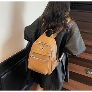 Close-up of brown pebbled leather backpack with silver zippers on a staircase
