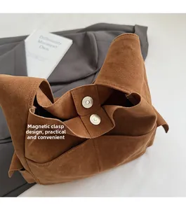 Détail de la fermeture à double boucle magnétique sur un sac fourre-tout en suède