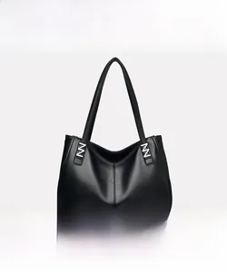 Detail of black pebbled leather tote bag featuring silver hardware and durable handles