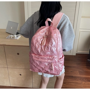 Close-up of pink quilted backpack with cute bear patterns and satin finish texture