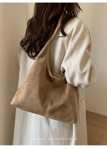 Brown suede hobo bag shown from a back view on a model wearing a trench coat