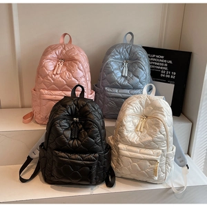 Detail of heart-quilted puffer backpacks in four colors showing the soft texture and pockets