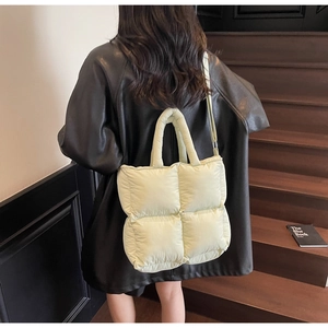 Detailed back view of a beige quilted tote bag worn by a model in a black leather jacket