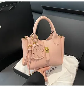 Pink lychee grain leather bucket bag featuring a cute dog charm and gold metal lock detail
