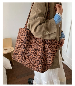 Detailed view of the large leopard print tote bag worn on a woman's shoulder