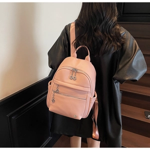 Detail of pink pebbled leather backpack with silver zippers and multi-pocket design