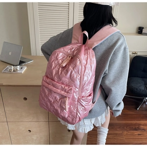 Rear view of model wearing pink quilted puffy backpack with unique bow textures