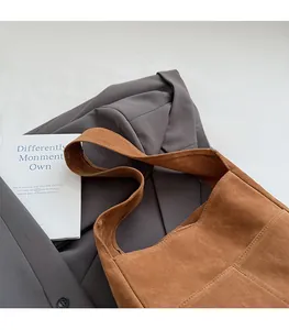 Détail du sac bandoulière en daim marron avec coutures décoratives et large sangle