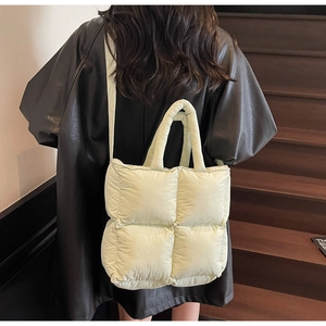 Close-up of light green quilted puffer tote bag with thick padded texture and shoulder strap