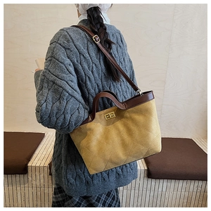 Détail du cabas matelassé jaune moutarde avec poignées en cuir marron et fermoir doré rotatif
