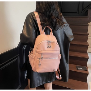 Pink pebbled leather backpack detail with multiple silver zippers on a model back