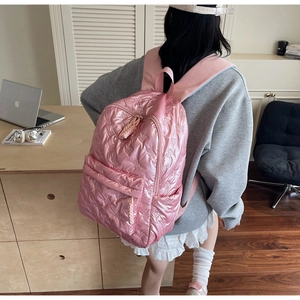 Pink quilted backpack with 3D bow texture shown in a modern lifestyle setting