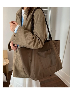 Detail of a brown canvas tote bag featuring leopard print straps and a large front pocket