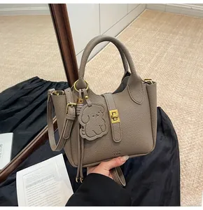 Detail of grey lychee leather bucket bag with gold rotary lock and dog charm