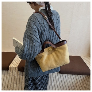 Détail d'un sac à main en daim jaune moutarde matelassé avec fermoir doré et poignée marron