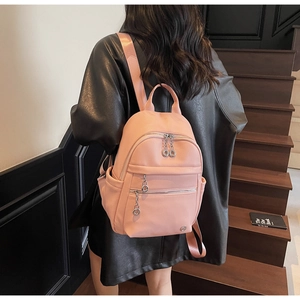 Rear view of a model wearing the pink lychee textured backpack with multiple zip pockets