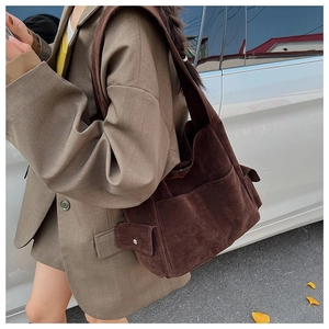 Détail du sac fourre-tout en daim marron foncé avec style rétro et poche latérale à boucle