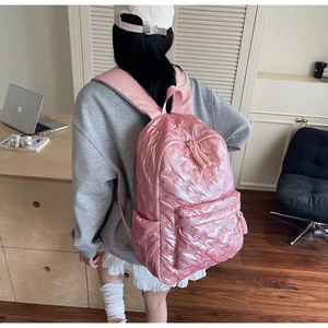 Detailed view of pink quilted puffy backpack with bow pattern and spacious front pocket
